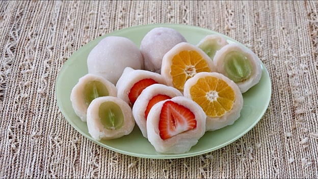 Daifuku Mochi (Japonya)

17. yüzyılda Japonya’da doğan daifuku mochi, pirinç unu hamurunun kırmızı fasulye ezmesiyle doldurulmasıyla yapılır. Özel günlerde tüketilen bu tatlı, modern versiyonlarda çilek, çikolata veya matcha dolgusuyla sunulur. Japonya’da dinî törenlerde de önemli bir yere sahiptir.