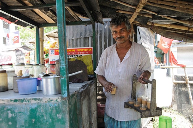 Hindistan’da Sokakların Chai Lezzeti
Hindistan’ın güneyinde çay, sokak kültürünün ayrılmaz bir parçası. “Chaiwala” adı verilen seyyar çay satıcıları, geniş kaplarda kaynattıkları çayı bardaklara doldurarak halka sunuyor. Siyah çay, süt, şeker ve kakule, karanfil, rezene gibi baharatlarla harmanlanıyor. Bu özel karışım, kilden yapılmış çaydanlıklarda demlenip cam bardaklarda ikram ediliyor. Chai, sadece bir içecek değil, aynı zamanda Hindistan’ın renkli sokaklarında dostlukların ve günlük hayatın bir yansıması.