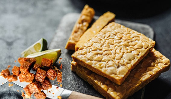 6. Tempeh
Endonezya’ya özgü tempeh, fermente soya fasulyesinden yapılan, protein açısından zengin bir gıdadır. Fındıksı aroması ve sıkı dokusuyla et alternatifi olarak tercih edilir. Probiyotikler ve B12 vitamini içerir; ayrıca fermentasyon süreci, soyanın besin emilimini engelleyen maddelerini parçalayarak vücudun mineralleri daha iyi kullanmasını sağlar.